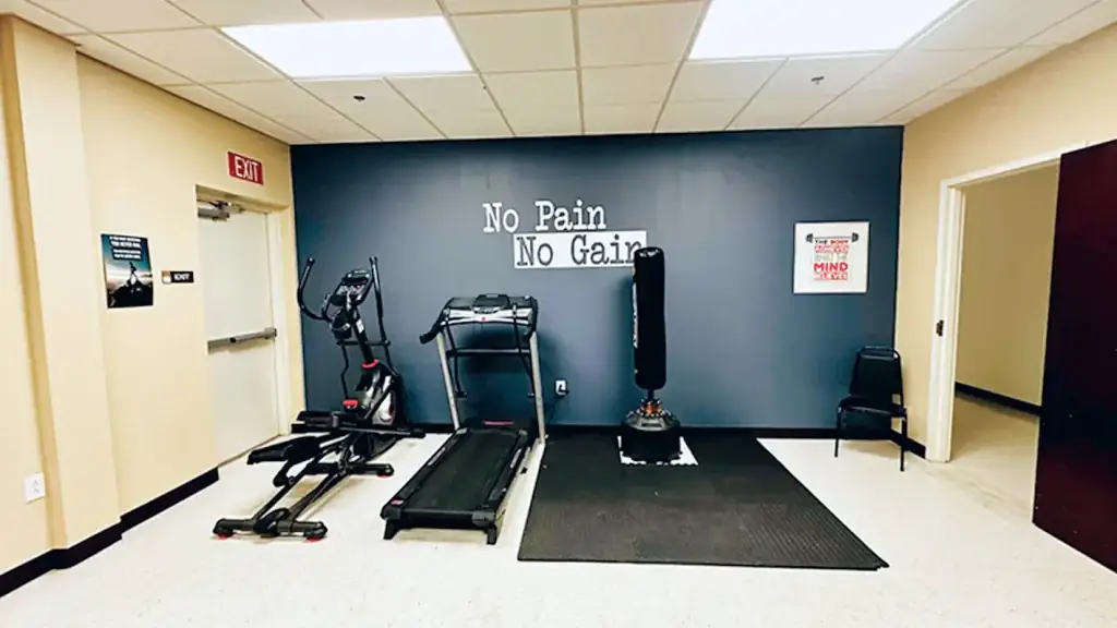 Texas Helps rehab exercise room with treadmill, punching bag and 'No Pain No Gain' text