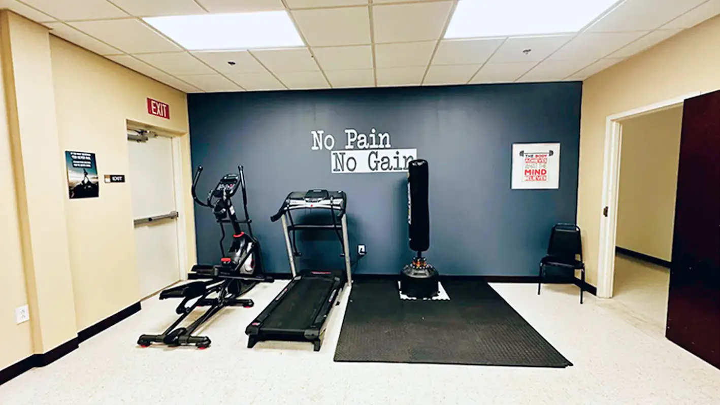 Texas Helps rehab exercise room with treadmill, punching bag and 'No Pain No Gain' text